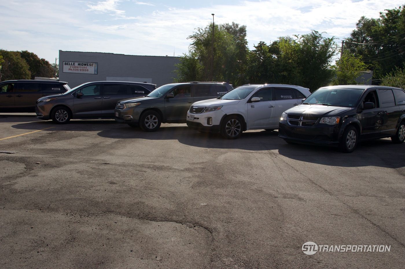 STL Transportation SUVs and minivans lined up, each with the company decal